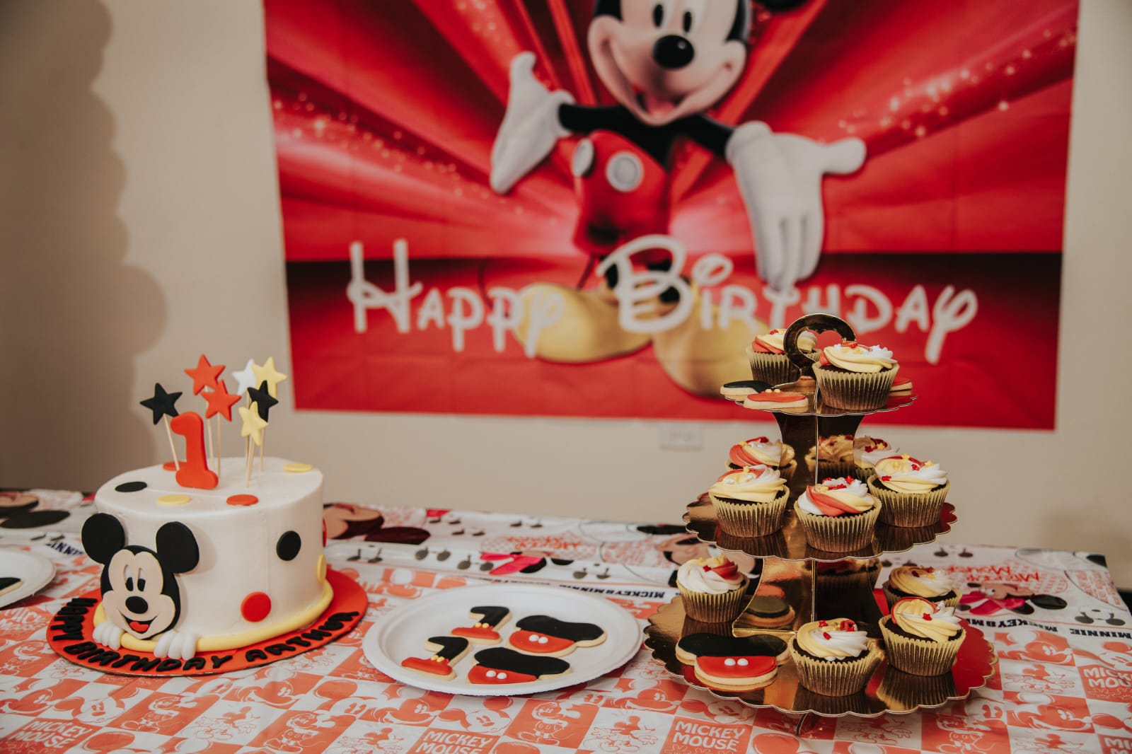 Mickey mouse theme party table with cake, cup cakes and decorated cookies